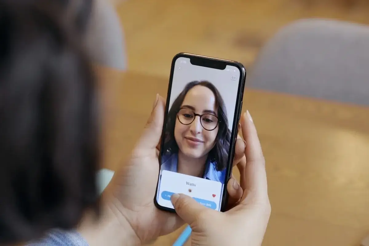 A lady looking at herself in the phone with AR lenses on her face